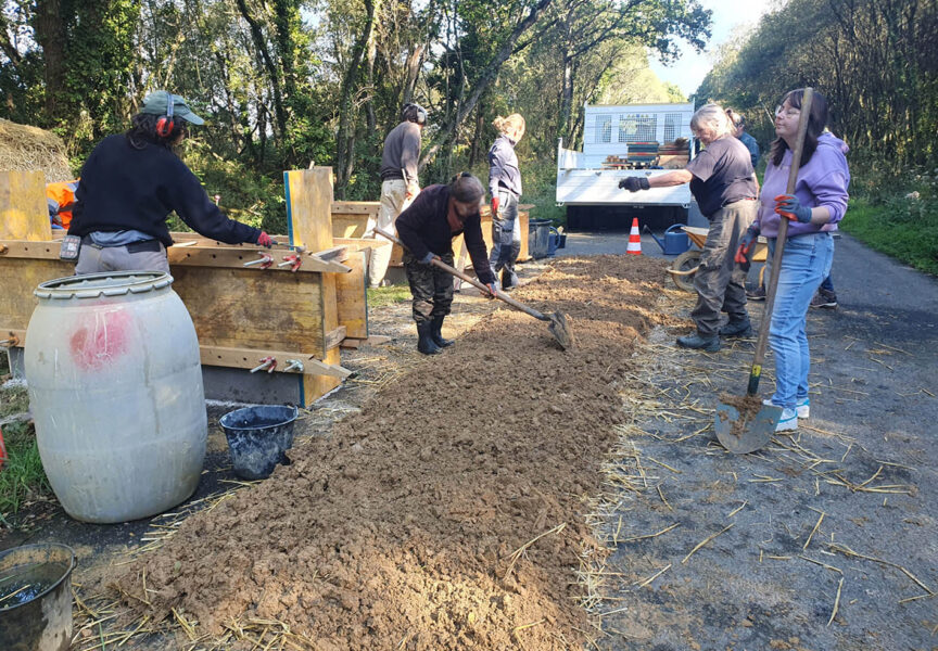 Des bénévoles construisent des murets en bauge sur la route des Landes.