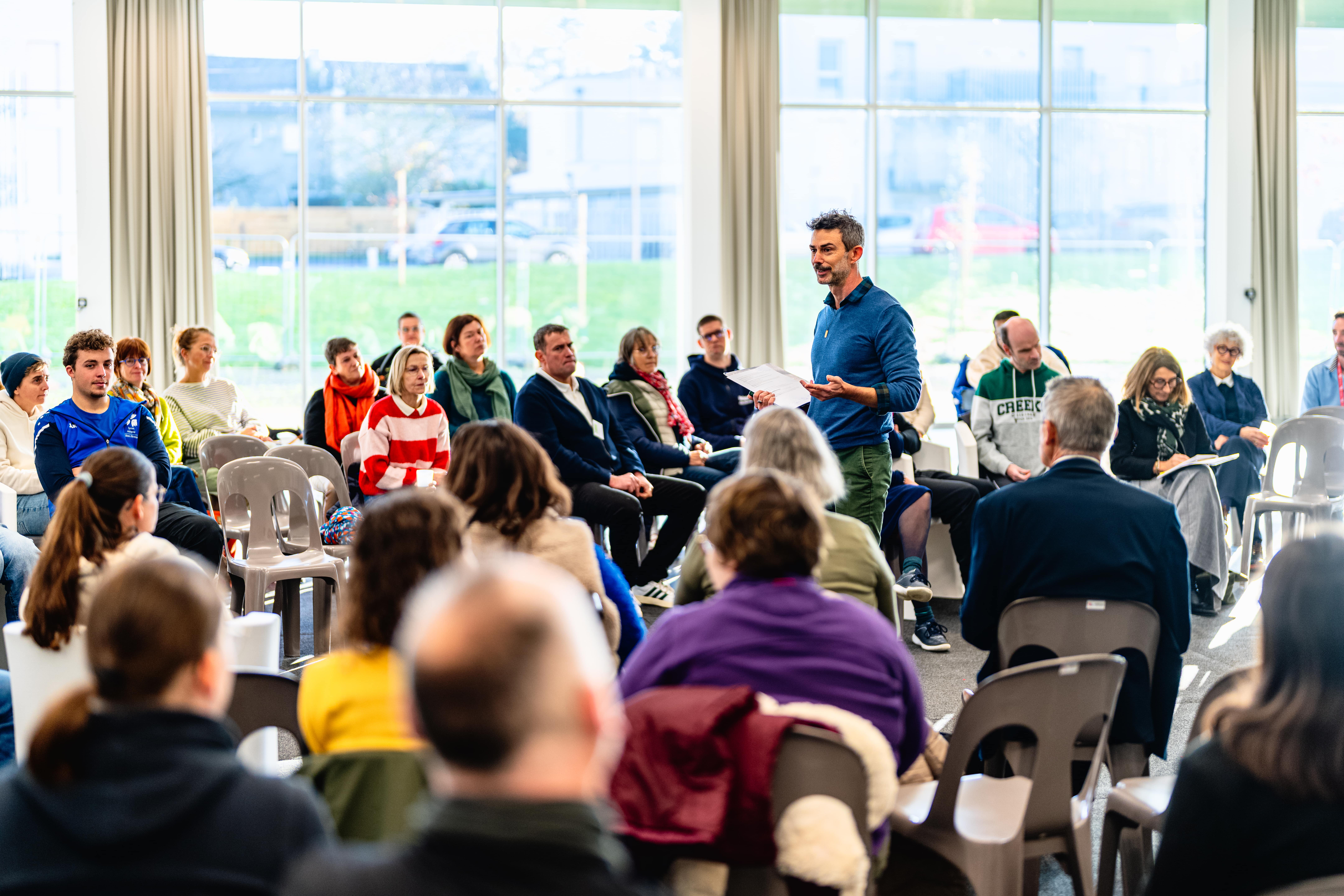 Groupe d'une trentaine de personnes assises, regardant et écoutant l'animateur, lors de la table ronde sur la loi de 2005.